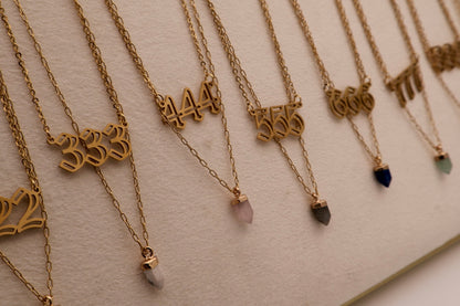 Gold necklaces with numbers and small stones on a light background