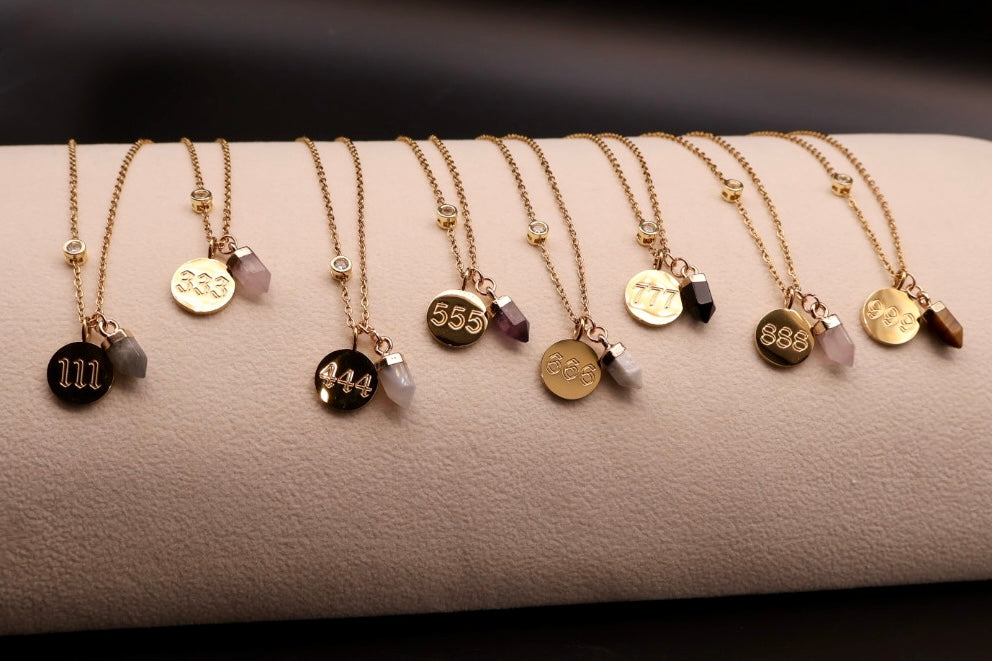 Row of gold necklaces with various pendants on a textured surface
