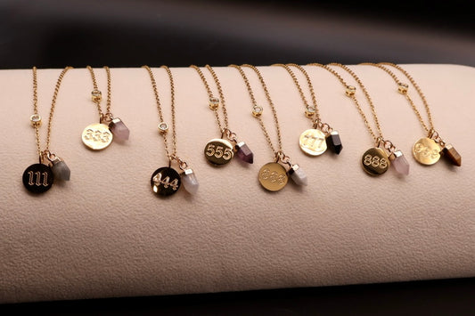 Row of gold necklaces with various pendants on a textured surface