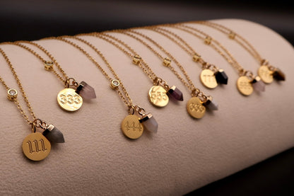 Gold necklaces with various pendants on a textured surface