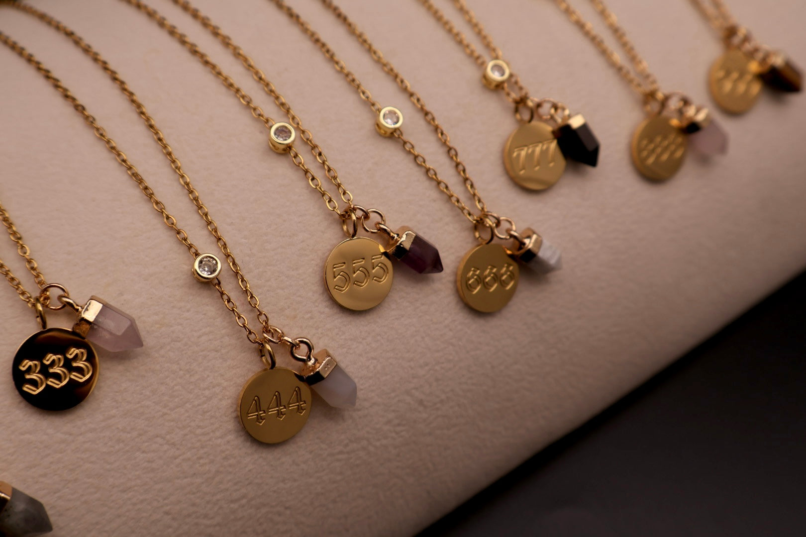 Gold necklaces with various pendants on a neutral background