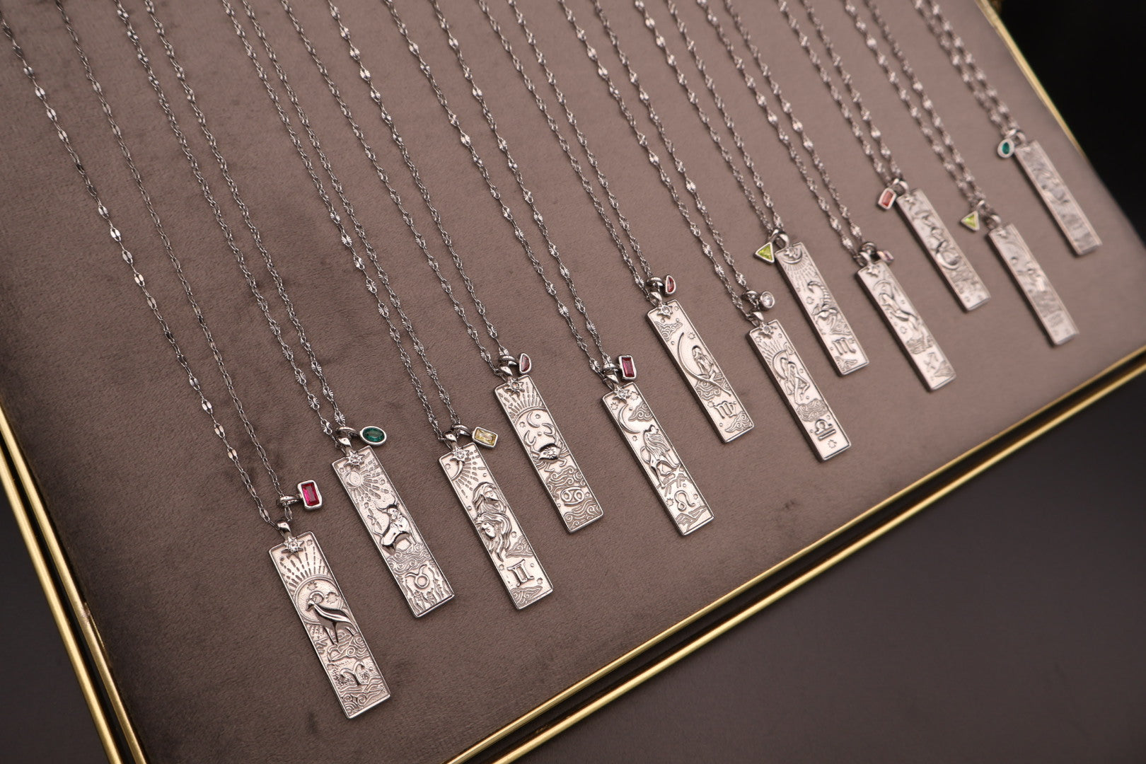 Row of silver necklaces with various pendants on a brown surface