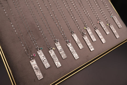 Row of silver necklaces with various pendants on a brown surface