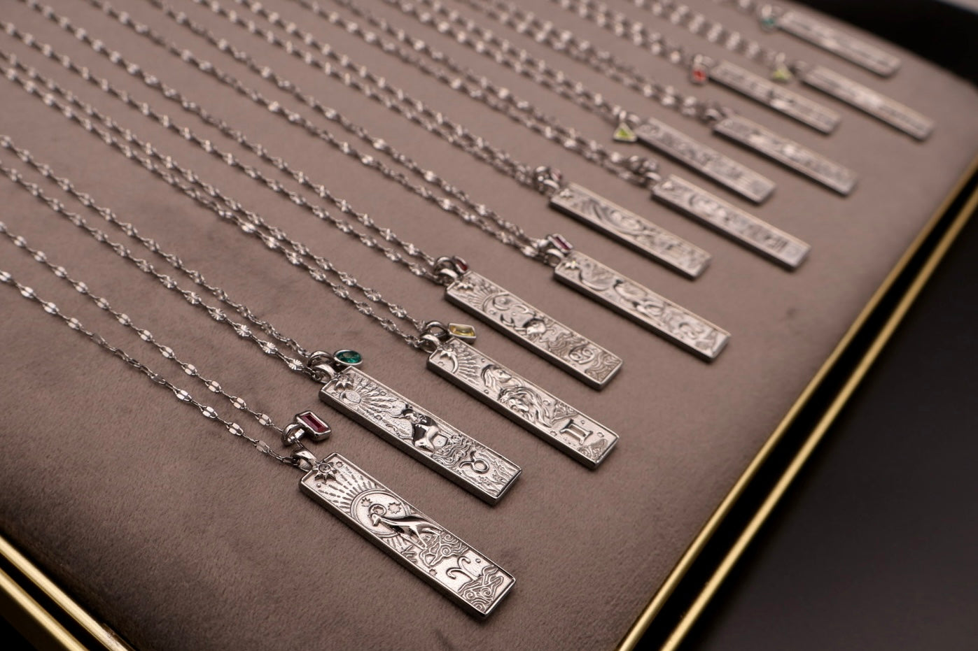Silver necklaces with engraved pendants on a brown display card.