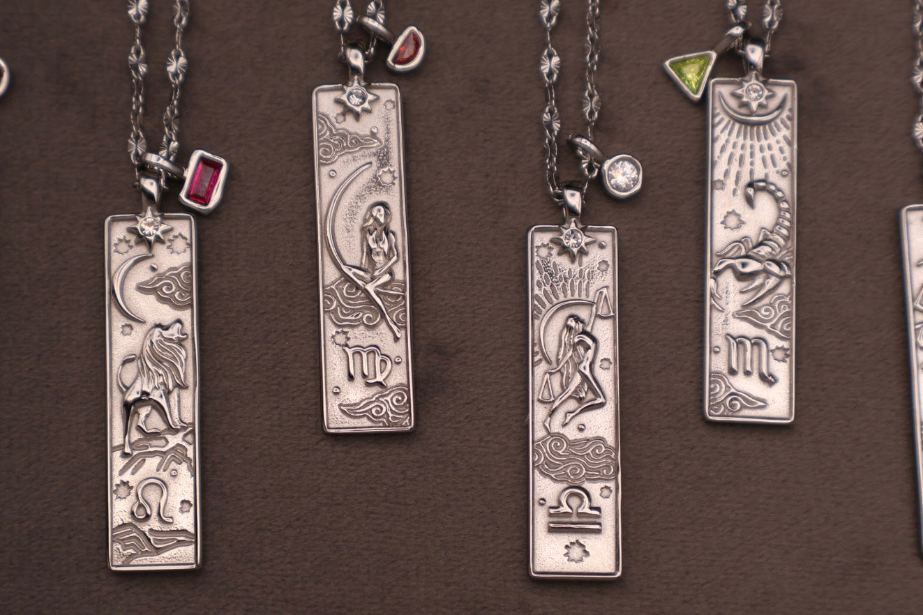 Collection of silver zodiac pendants on a brown background