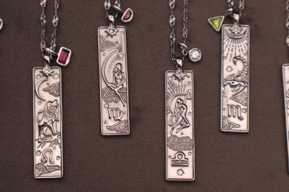 Collection of silver zodiac pendants on a brown background