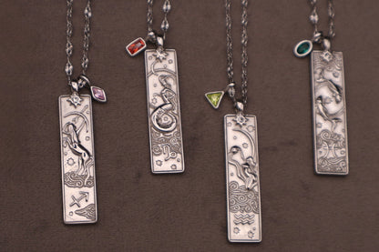 Set of silver necklaces with rectangular pendants on a brown background