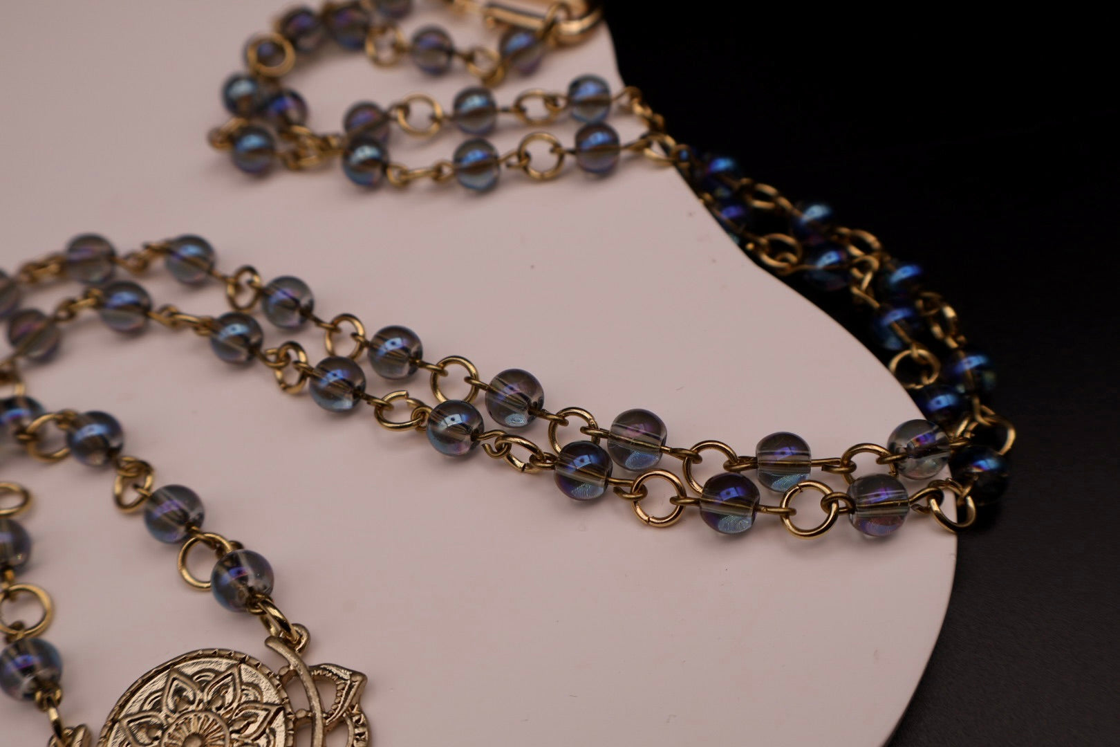 Necklace with blue beads and gold chain on a white surface