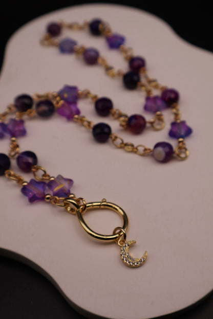 Necklace with purple beads and gold clasp on a white surface
