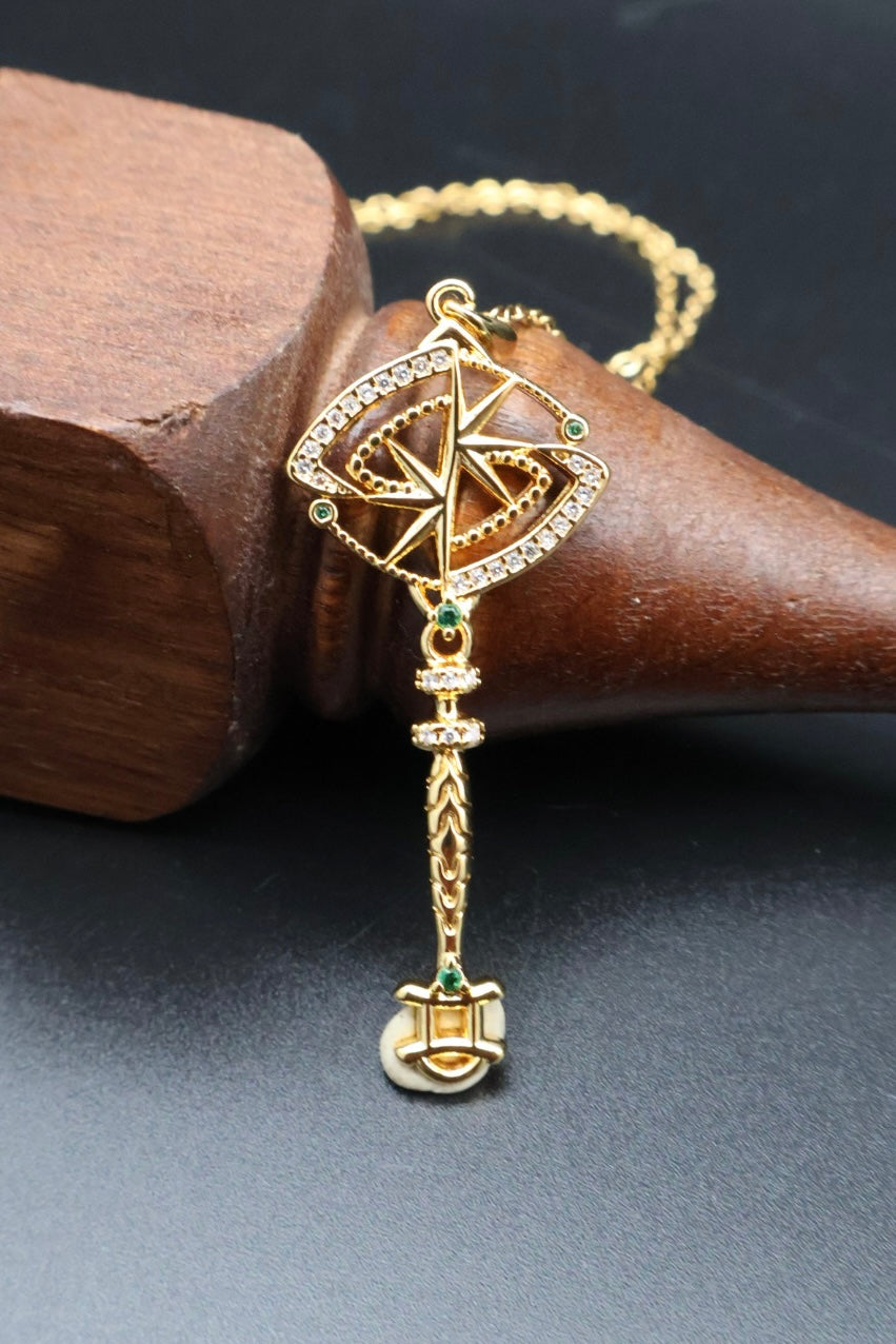 A gold-toned traditional Indian pendant necklace with a compass design and hanging tassel, displayed on a dark surface next to a wooden block.