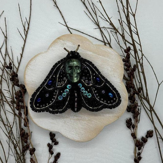 a pin of a deaths head hawkmoth pin with a labradorite skull.