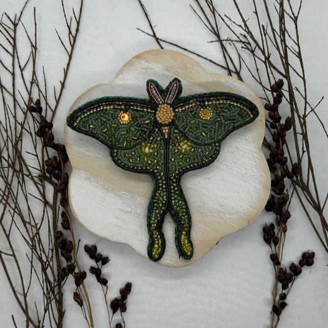 a beaded luna moth pin with green beads of various shades