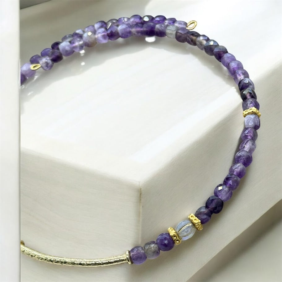 A flexible choker adorned with purple stones and gold accents, featuring an elegant and timeless design."