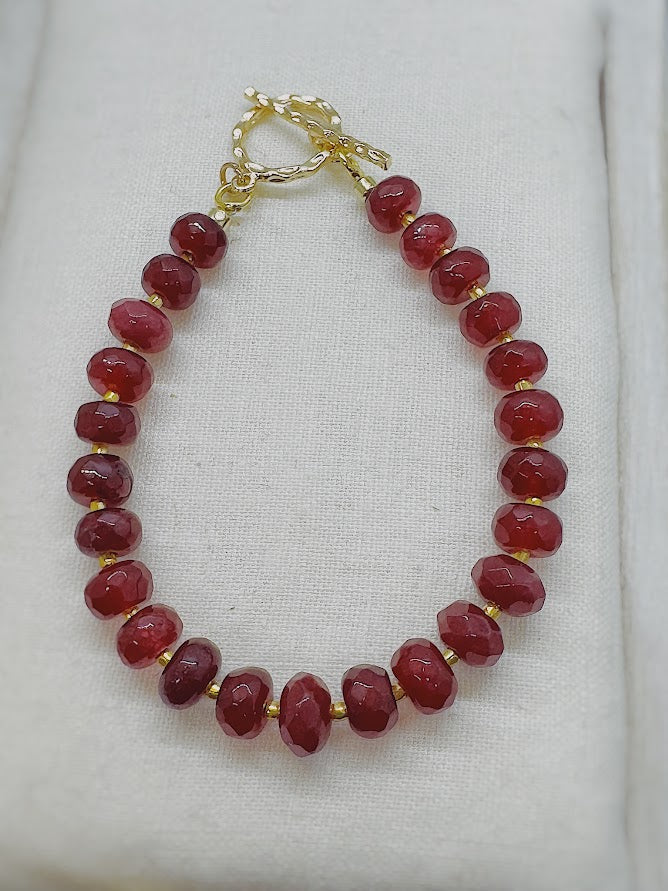 a bracelet made with ruby colored beads