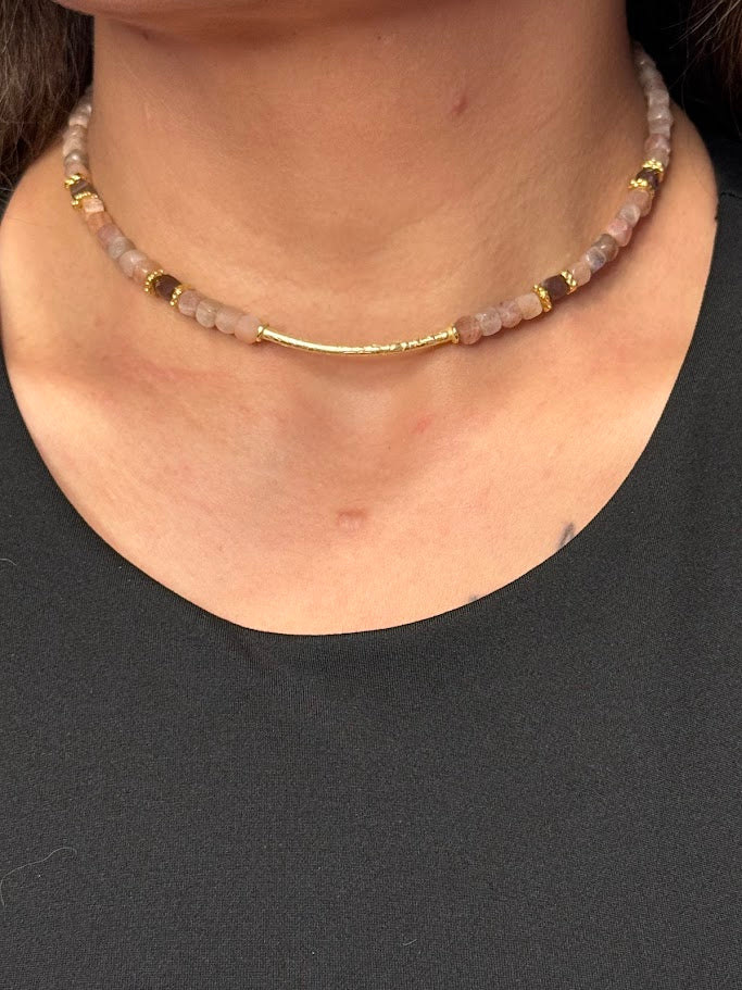 A woman wearing a choker made up of sunstone beads with gold accents. 