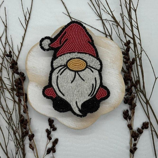 a bead embroidered pin of a Christmas gnome with a Santa hat on