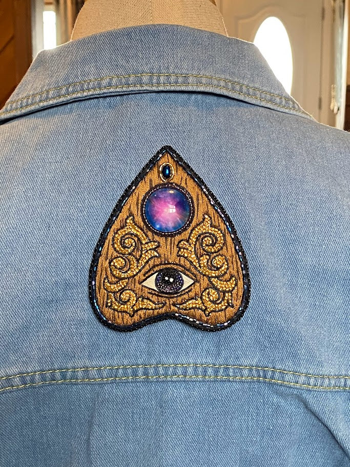 a planchette pin on the back of a denim jacket