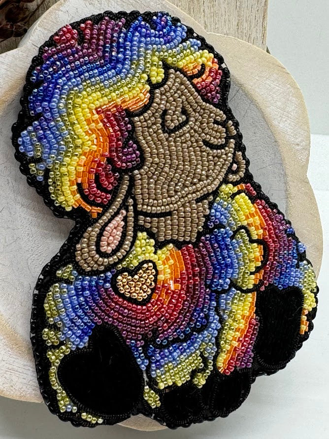 a closeup of a pin of a happy rainbow sheep with a gold heart