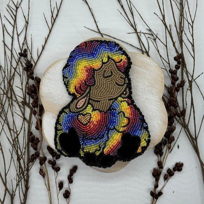 a pin of a happy rainbow sheep with a gold heart