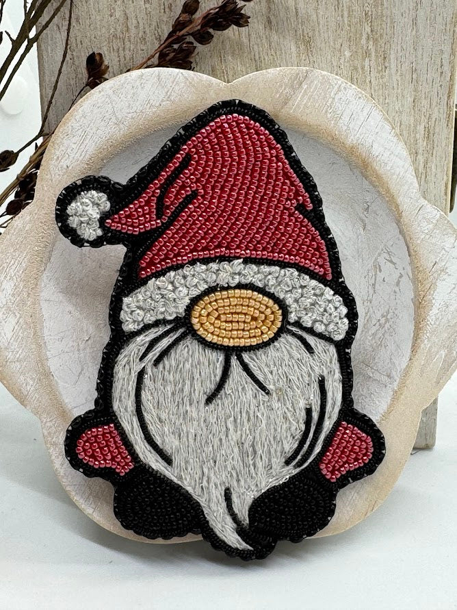 a bead embroidered pin of a Christmas gnome with a Santa hat on