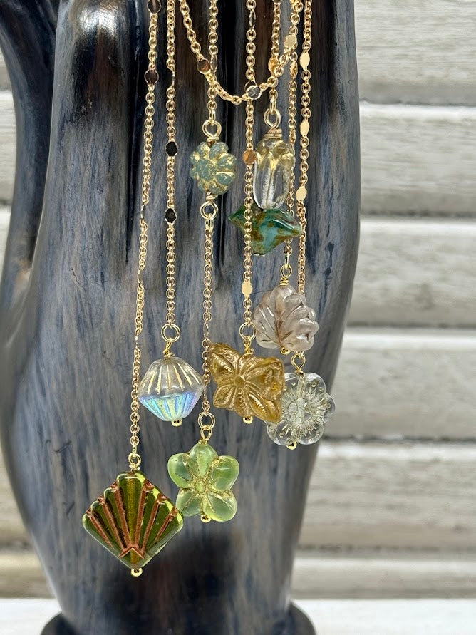 a closeup of an ear hanger with gold chains and baroque style, butterfly, and flower beads.