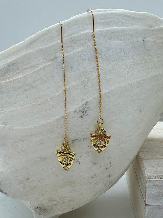Evil Eye Threader Earrings worn outdoors in natural light, with the eye design catching the light, adding a mystical touch to the wearer’s look.
