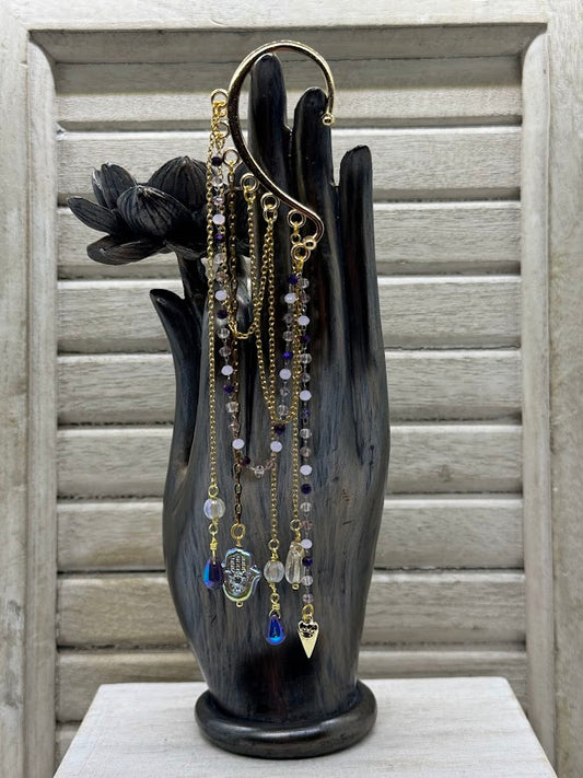 an ear hanger with beaded and gold chains and charms hanging from them.